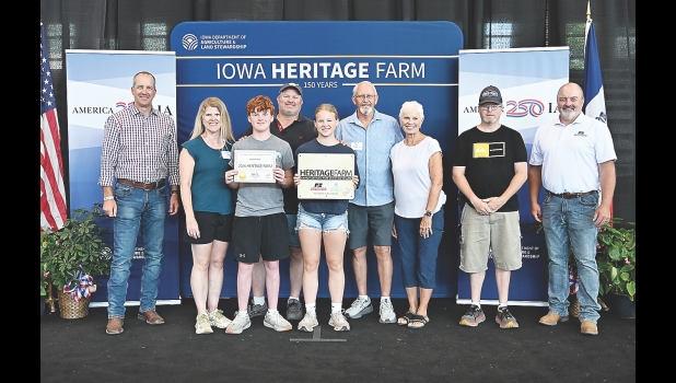 Iowa Secretary of Agriculture Mike Naig (left) and Iowa Farm Bureau Federation President Brent Johnson (right) presented the Rugland family with the Iowa Heritage Farm award at a ceremony on August 20 during the Iowa State Fair.